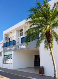 a palm tree in front of a hotel at Treville Hotel in Caràzinho