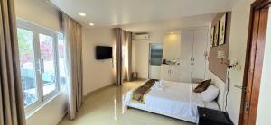 a bedroom with a white bed and a large window at Hugo Hotel in Phú Quốc