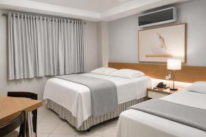 a hotel room with two beds and a table at Treville Hotel in Caràzinho +55 photos