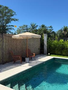 an umbrella and chair next to a swimming pool at Casa Tierra Esmeralda in Parrita