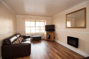 a living room with a leather couch and a television at Single Room with shared bathroom in Cheshunt