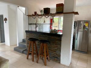 a kitchen with a bar with two stools and a refrigerator at Casa para 6 personas con vista al mar Cumbre del Diablo 3 in Punta Del Diablo