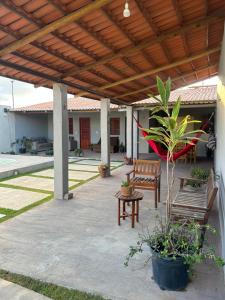 a patio with two benches and a wooden pergola at Recanto Esmeralda in Fortim