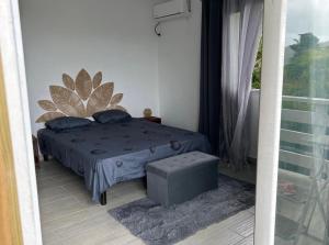 a bedroom with a bed with blue pillows and a window at Bungalow Kaz à Céli in Deshaies