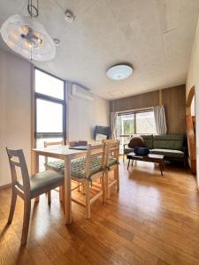 a living room with a table and chairs and a couch at トラストメゾン荻 in Ito