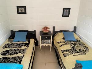 two beds in a room with a side table at Casa para 6 personas con vista al mar Cumbre del Diablo 3 in Punta Del Diablo