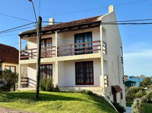 a white house on a grassy hill at Brisas del Diablo 1 in Punta Del Diablo +8 photos