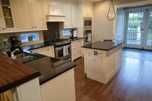 a large kitchen with white cabinets and black counter tops at Middletown Bungalow w/Hot Tub and Private Yard - RIBryan Properties in Middletown