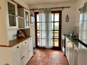 a kitchen with white cabinets and a door with a window at Brisas del Diablo 1 in Punta Del Diablo