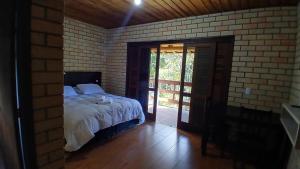 a bedroom with a bed and a brick wall at Pousada Rural Encanto do Riacho in Bom Jardim da Serra