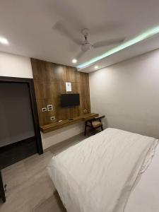a bedroom with a bed and a tv on the wall at Ganges Pride Hotel in Haridwār