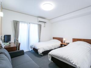 ein Hotelzimmer mit zwei Betten und einer Couch in der Unterkunft HOTEL Calmplace in Kanda