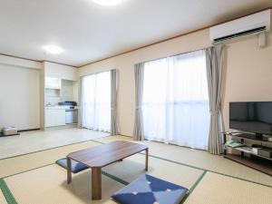 ein Wohnzimmer mit einem Tisch und einem Fernseher in der Unterkunft HOTEL Calmplace in Kanda