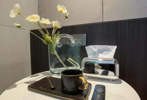 a vase of flowers sitting on a table with a coffee cup at Xi'an Jing - Scenery Hotel in Xi'an +192 photos
