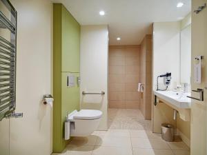 
a bathroom with a toilet, sink, and shower at Golden Tulip Amnéville in Amnéville
