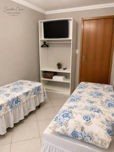 a bedroom with two beds and a tv on a shelf at Hotel Pousada Santa Ceia in Aparecida