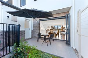 a patio with a table and chairs and an umbrella at Homenest in Gledswood Hills