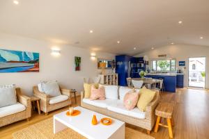 a living room with two couches and a table at Beachfront 25 The Strand Moana in Waiheke Island