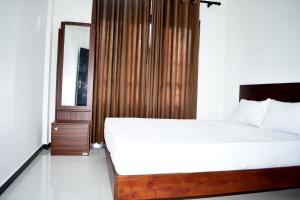 a bedroom with a large bed and a mirror at Lasya Residence in Trincomalee