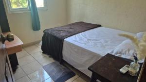 a small bedroom with a bed and a table at Residencial Acropolis in Sonsonate