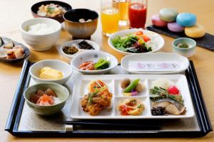 a table with a plate of food and bowls of food at The Kanazawa Sainoniwa Hotel in Kanazawa