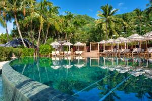 a pool at a resort with palm trees and umbrellas at Sofitel Kia Ora Moorea Beach Resort in Maharepa