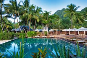 a resort with a swimming pool with tables and umbrellas at Sofitel Kia Ora Moorea Beach Resort in Maharepa