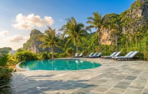 a swimming pool with chairs and mountains in the background at Cabalina Grove in Ðảo Cát Bà