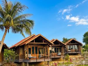 a house with a palm tree in front of it at Cabalina Grove in Ðảo Cát Bà