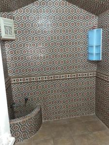 a bathroom with a patterned wall with a chair at Tafoukt 2 in Kasba Aït Youdi