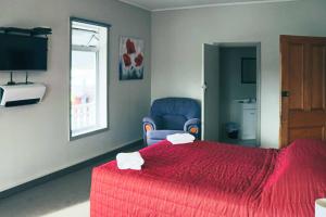 a bedroom with a red bed and a blue chair at Hampden Hotel Murchison in Murchison