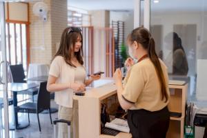 two women standing in an office looking at their cell phone at JT Place Buriram in Buriram