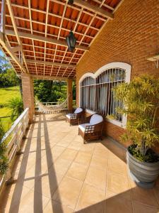 an outdoor patio with chairs and a wooden pergola at Pousada Sítio das Cerejeiras in São Roque