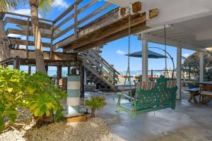 a green chair hanging from a porch with a view of the ocean at Blanco Bay Key in Duck Key