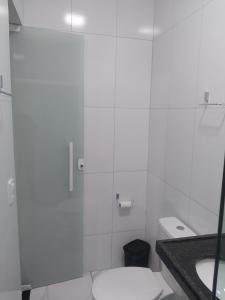 a white bathroom with a toilet and a sink at Pousada Triângulo in Juazeiro do Norte
