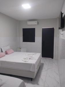a bedroom with two beds and a flat screen tv at Pousada Triângulo in Juazeiro do Norte