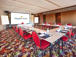 une salle de conférence avec des tables, des chaises rouges et un écran dans l'établissement Golden Tulip Amnéville, à Amnéville