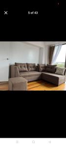 a living room with a brown couch and a window at Gigi's transient house in Baguio