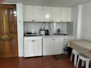 a kitchen with white cabinets and a sink and a table at Gigi's transient house in Baguio