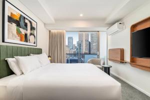 a bedroom with a large white bed and a large window at Urban Rest Melbourne in Melbourne