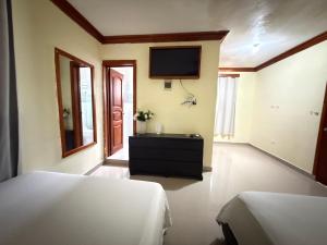 a bedroom with two beds and a tv on the wall at Aparta hotel doble in Higuey