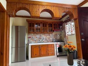 a kitchen with wooden cabinets and a refrigerator at Aparta hotel doble in Higuey +3 photos