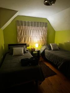 two beds in a room with green walls and a window at Hostal el valle in Angol