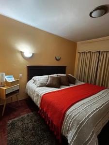 a bedroom with a large bed with a red blanket at Hostal el valle in Angol
