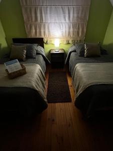 a bedroom with two beds and a lamp on a wooden floor at Hostal el valle in Angol