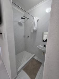 a white bathroom with a shower and a sink at SADO Guesthouse in Katima Mulilo