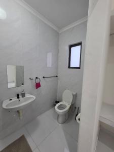 a white bathroom with a toilet and a sink at SADO Guesthouse in Katima Mulilo +1 photo