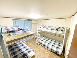 a room with three bunk beds and a window at ＧＵＥＳＴ　ＨＯＵＳＥ　てぃんが〜ら in Sobe