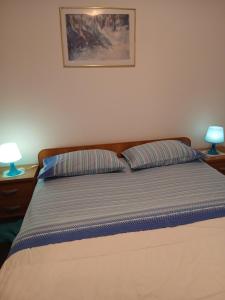 a bed in a bedroom with two lamps on tables at Gita in Omišalj