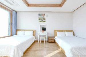 two beds in a room with a table and a mirror at Jeju DK House Pension in Seogwipo